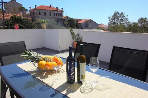 a table with two bottles of wine and a bowl of fruit at Apartment Milenka in Čilipi