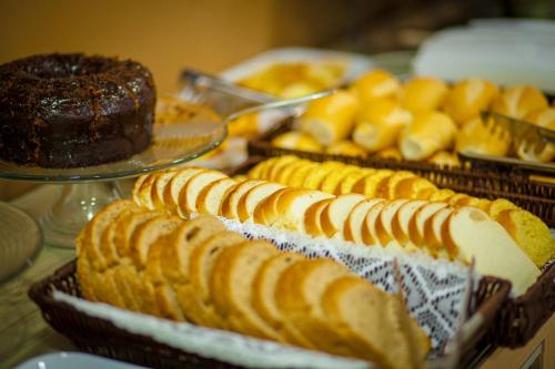 a table with several trays of bread and cakes at CLH Suítes Foz do Iguaçu in Foz do Iguaçu