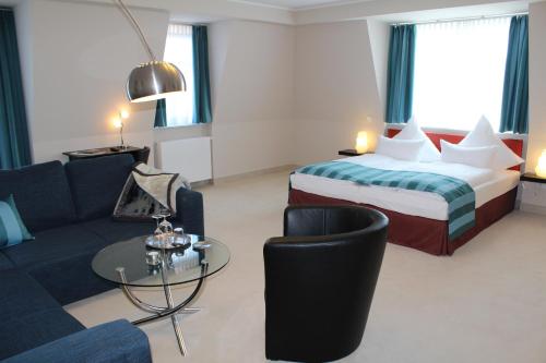 a hotel room with a bed and a couch and a table at Pension Strandschloss Arielle in Börgerende-Rethwisch