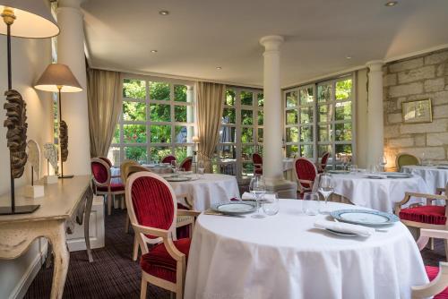 a restaurant with white tables and chairs and windows at Hôtel la Magnaneraie in Villeneuve-lès-Avignon