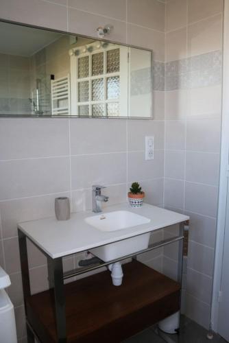 une salle de bain avec un lavabo blanc et un miroir dans l'établissement LE MASCARET 47 b Gîte touristique 3 étoiles, à Bricqueville-sur-Mer