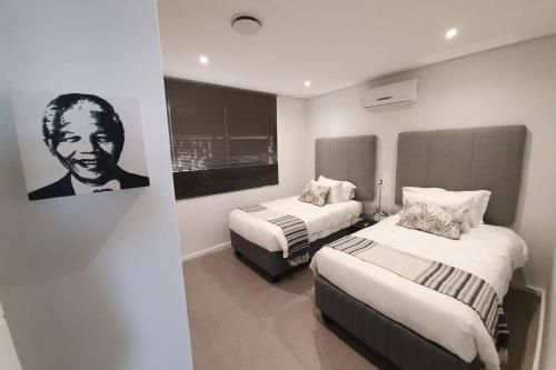 Zimmer mit 2 Betten und einem Bild eines Mannes in der Unterkunft Luxury Apartment near the Airport with Sea View in Umhlanga