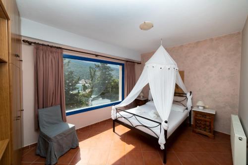 a bedroom with a canopy bed with a window at Natassa Apartments Penthouse sea view 30m from sea in Ayia Evfimia