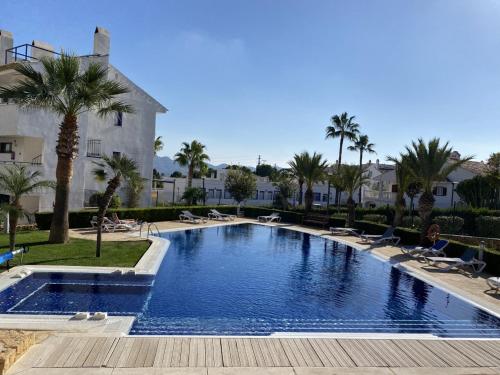 une grande piscine bordée de palmiers et de chaises dans l'établissement Alfaz del Sol, à L'Alfàs del Pi