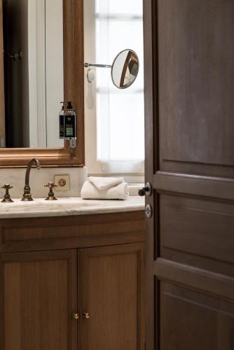 a bathroom with a sink and a mirror and a door at Hôtel la Magnaneraie in Villeneuve-lès-Avignon