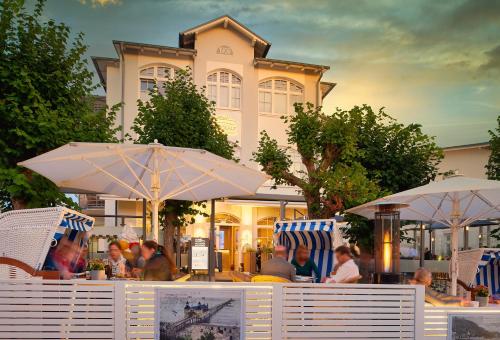 a group of people sitting at a table with umbrellas at Hotel Glückauf 1908 in Ostseebad Sellin