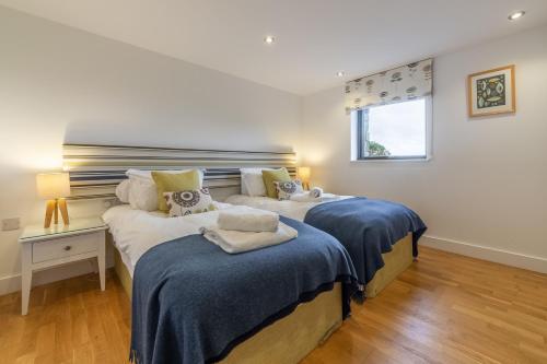 Un dormitorio con dos camas con sábanas azules y una ventana. en Teyr Mor Cliff, en St. Agnes