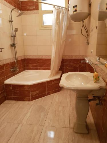 y baño con bañera, aseo y lavamanos. en Elite Homes 3BR Garden Apartment Families Only en 6th Of October