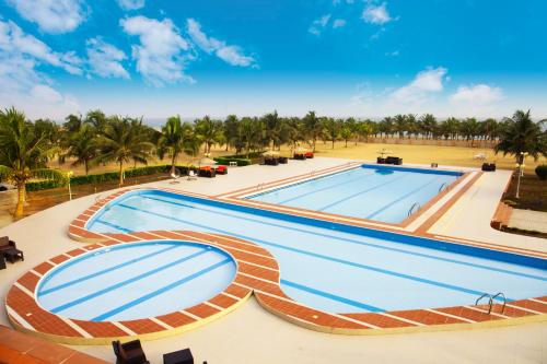 a large swimming pool with palm trees in the background at Millenium Popo Beach Hotel in Grand-Popo
