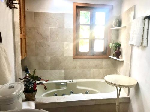 a bathroom with a tub and a window and a toilet at CASA DEL TEATRO Luxury Casas Vejer Debra in Vejer de la Frontera