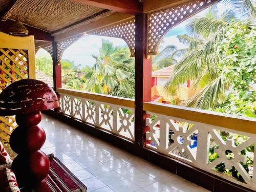 a balcony with a view of a palm tree at Maison Couleur Passion in Nianing