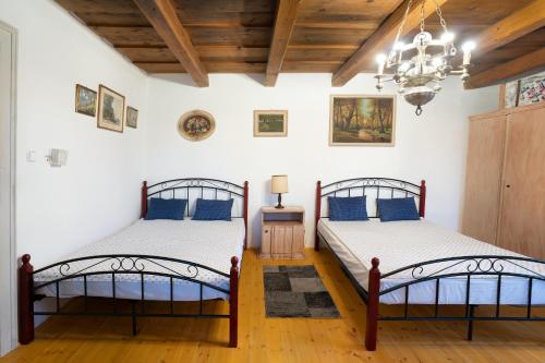 two beds in a room with white walls and wooden floors at Magdolna Vendégház Magánszálláshely in Écs