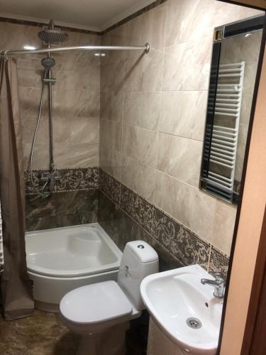 a bathroom with a toilet and a sink and a tub at Mountain Residence in Tukhlya