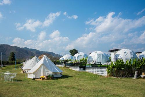a group of tents in a field with mountains in the background at ไร่บำรุงผล Raibumrungphol in Mae Wang