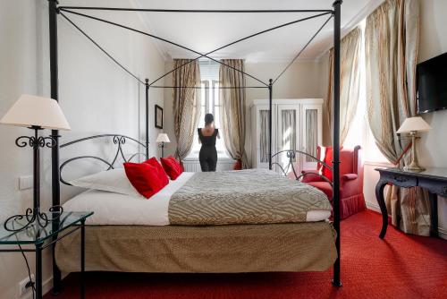 a woman is standing in a bedroom with a bed at Hôtel de L'univers in Arras