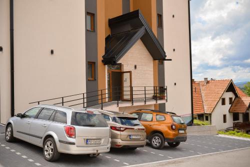 three cars parked in a parking lot in front of a building at Apartman Moj kutak Zlatibor in Zlatibor