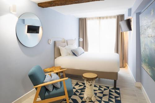 ein Schlafzimmer mit einem Bett, einem Stuhl und einem Spiegel in der Unterkunft Appart hôtel Maison Montgrand-Vieux Port in Marseille