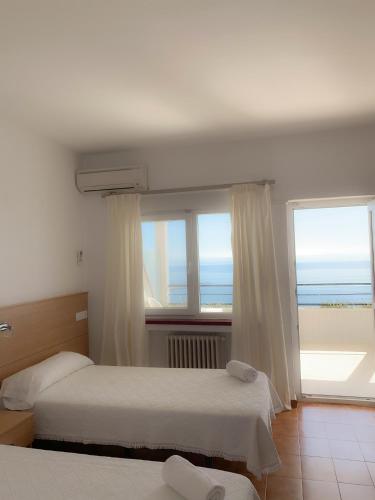 two beds in a room with a view of the ocean at Hotel Patricia in Torreguadiaro