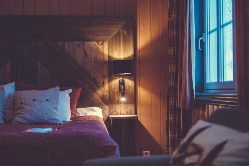 a bedroom with a bed and a lamp and a window at Gudbrandsgard Hotel in Kvitfjell