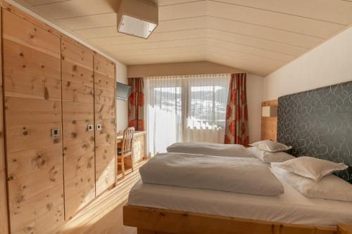 a bedroom with two beds in a room with wooden walls at Garni Ciasa Tamà in Corvara in Badia