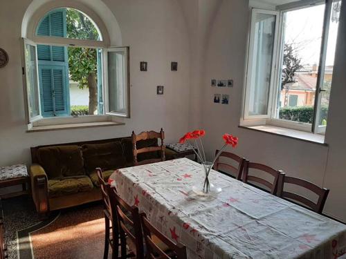 una sala de estar con una mesa con flores rojas. en Casa Gazzano, en Imperia