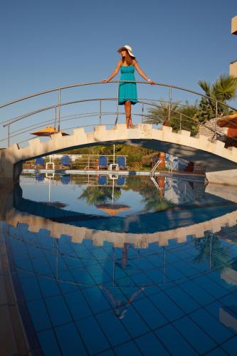 a woman standing on a bridge over a swimming pool at Oasis Scaleta Hotel in Skaleta