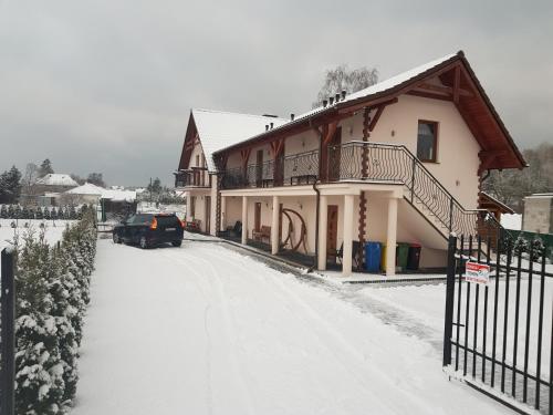 una casa en la nieve con un coche aparcado en la entrada en Pokoje Mariola, en Sztutowo