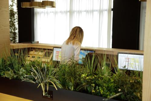 a woman standing at a counter with plants at Royal G Hotel and Spa in Durrës
