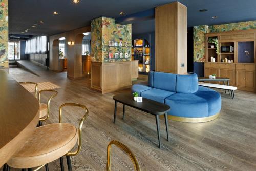 a lobby with a blue couch and tables and chairs at Hôtel Marielle in Val Thorens