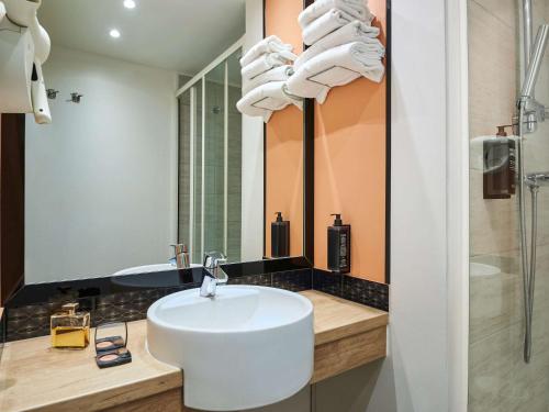 uma casa de banho com um lavatório branco e um chuveiro em Ibis Styles Paris Gennevilliers em Gennevilliers