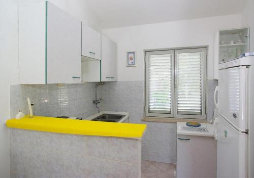 a kitchen with a yellow counter top and a white refrigerator at Apartments Tomašić in Smokvica