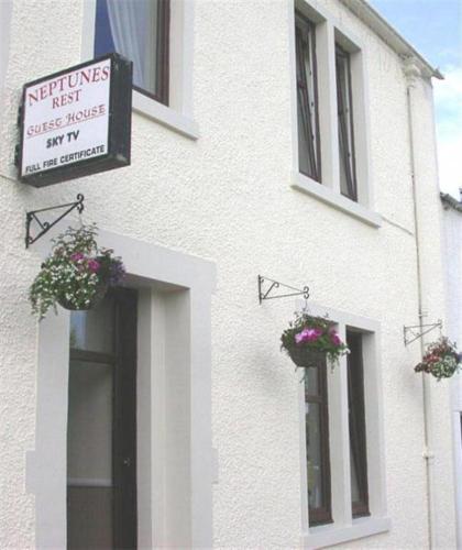ein weißes Gebäude mit zwei Fenstern mit Blumentöpfen darauf in der Unterkunft Neptunes Rest Guest Hotel in Stranraer