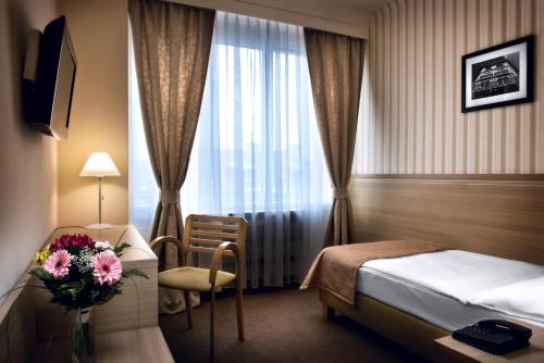 a hotel room with a bed and a vase of flowers at Hotel Tatra in Bratislava