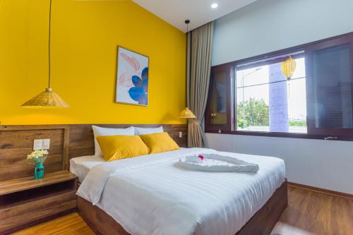 a bedroom with a large bed with a yellow wall at SOLEIL BOUTIQUE in Hue