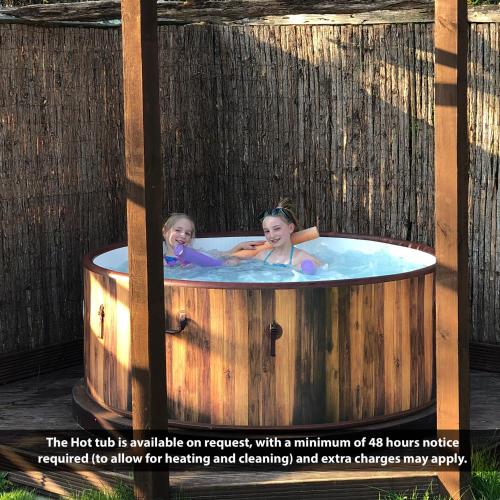 two children are in a jacuzzi in a wooden tub at Luxurious Rural Cabin with Hot Tub in West Chiltington