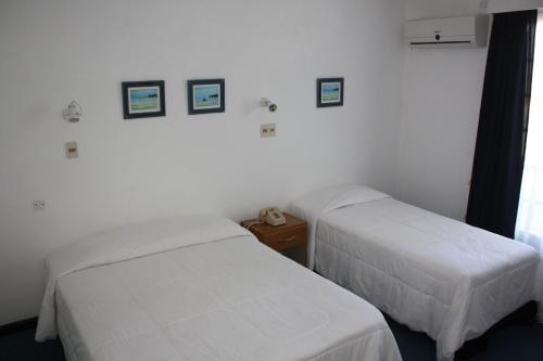 two beds in a room with white walls at Hotel Escorial in Piriápolis