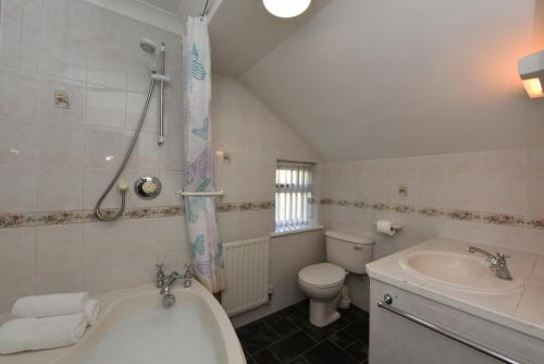 a bathroom with a tub and a toilet and a sink at The Mews in Dartmouth