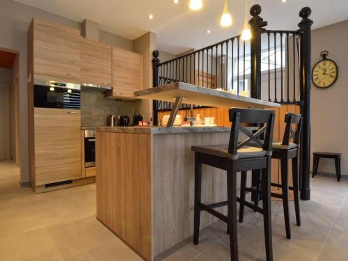 een keuken met een bar met krukken en een trap bij Splendid ground floor apartment with garden in the very center of Spa in Spa