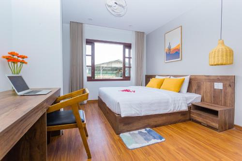 a bedroom with a bed and a desk with a laptop at SOLEIL BOUTIQUE in Hue