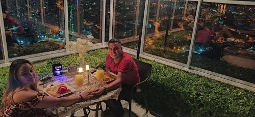 a man and a woman sitting at a table with food at Terraço Harmony Flats GRU in Guarulhos