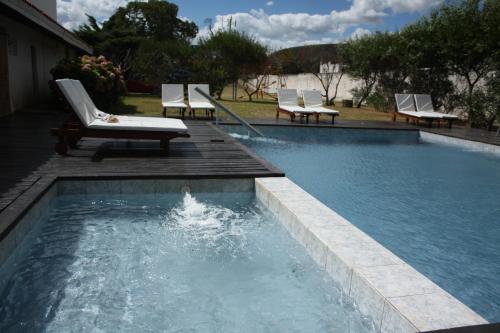 a swimming pool with chaise lounge chairs and a swimming pool at Hotel Escorial in Piriápolis