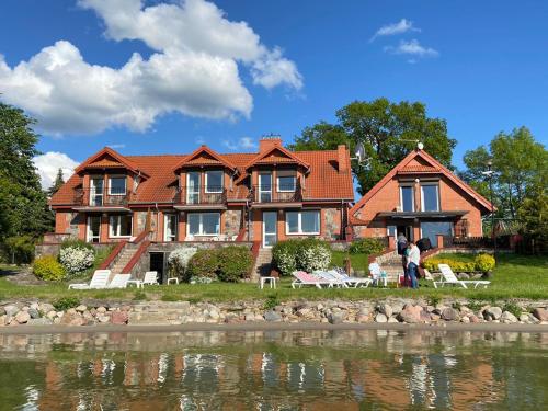 duży dom z jeziorem przed nim w obiekcie Panorama Lake Resort w mieście Nowe Guty