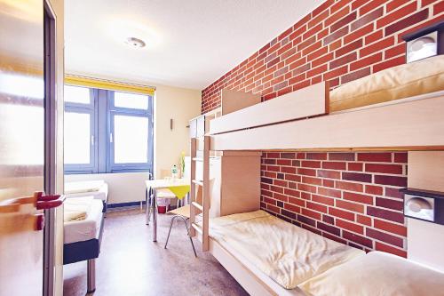 a room with bunk beds and a brick wall at Jugendgästehaus Aasee in Münster