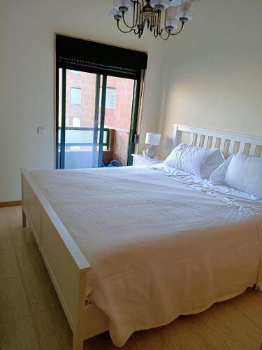een groot wit bed in een slaapkamer met een raam bij Beautiful first line beach apartment Samil in Vigo