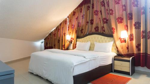 a bedroom with a large white bed and curtains at Millenium Popo Beach Hotel in Grand-Popo