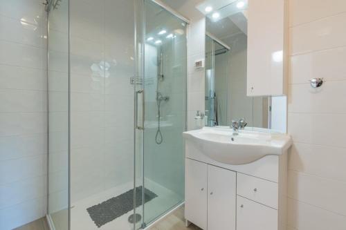 La salle de bains est pourvue d'une douche en verre et d'un lavabo. dans l'établissement Irma Apartment, à Dajla
