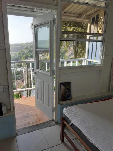Schlafzimmer mit einer Tür, die auf einen Balkon führt in der Unterkunft Cosy Hut in Saint Georgeʼs