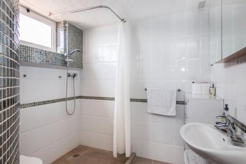 a white bathroom with a shower and a sink at Sunset Balcony with Ocean Views and pool access in Mogán