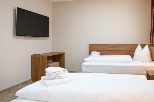 a hotel room with two beds and a flat screen tv at Work & Sleep Boardinghouse Mannheim in Mannheim