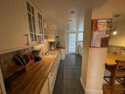 Una cocina con gabinetes blancos y una encimera de madera. en Serendipity, en Broadstairs